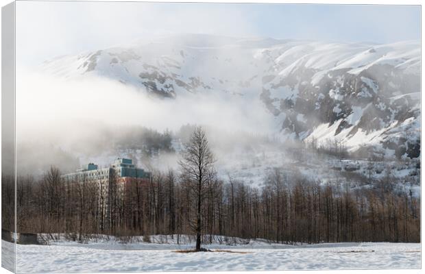 Mist and Fog swirls around Begich Towers Condominium building and the mountains behind, Whittier, Alaska, USA Canvas Print by Dave Collins