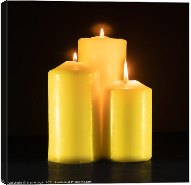 Three burning candles in the darkness Canvas Print by Bryn Morgan