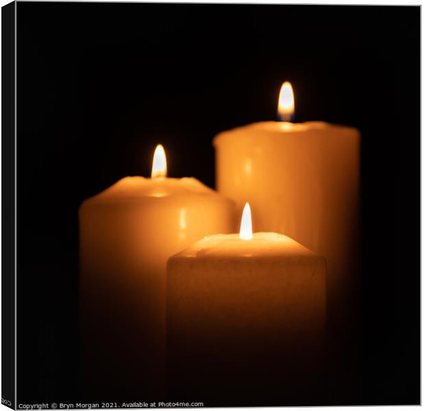 Three burning candles in the darkness Canvas Print by Bryn Morgan