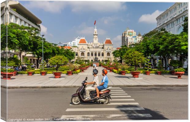 A motorcyclist rides along the road.past a statue of Ho Chi Minh Canvas Print by Kevin Hellon