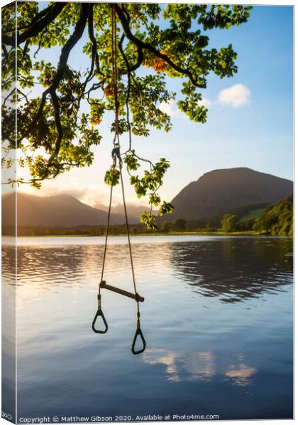Quintessential beautiful English Summer landscape image of child's rope swing over calm lake in Lake District during golden Summer sunrise Canvas Print by Matthew Gibson