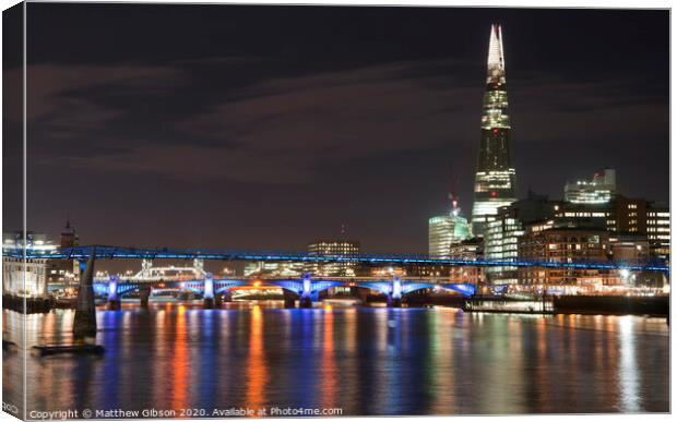 Beautiful landscape image of the London skyline at night looking along the River Thames Canvas Print by Matthew Gibson