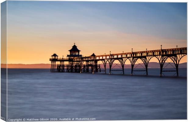 Beautiful long exposure sunset over ocean with pier silhouette Canvas Print by Matthew Gibson