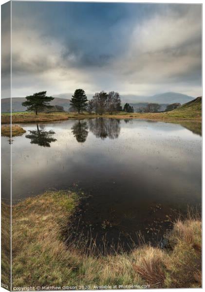 Stunning landscape image of dramatic storm clouds over Kelly Hall Tarn in Lake District during late Autumn Fall afternoon Canvas Print by Matthew Gibson