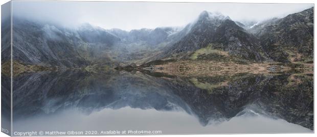 Beautiful moody Winter landscape image of Llyn Idwal and snowcapped Glyders Mountain Range in Snowdonia Canvas Print by Matthew Gibson