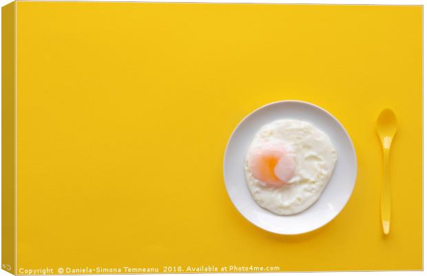 Fried egg in a plate on a yellow background Canvas Print by Daniela Simona Temneanu