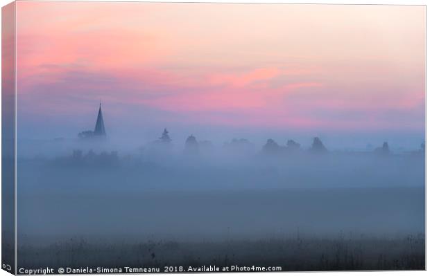 Church tower and village in fog at dawn Canvas Print by Daniela Simona Temneanu