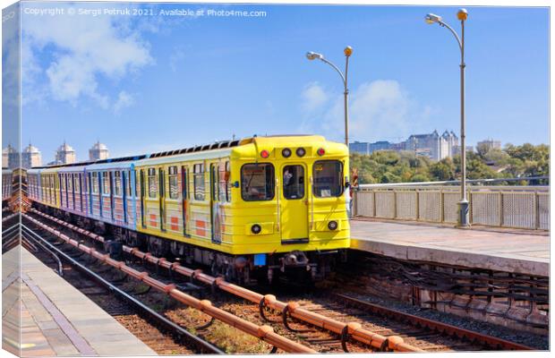 A bright yellow metro train departs from the platform and rushes along the metro bridge in Kyiv to the left side of the city. Canvas Print by Sergii Petruk