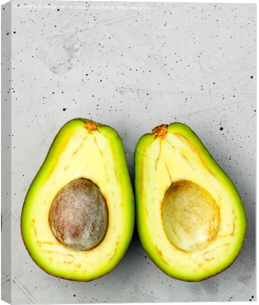 Avocado, cut in half, one slice with a core, on a gray concrete background, top view. Canvas Print by Sergii Petruk