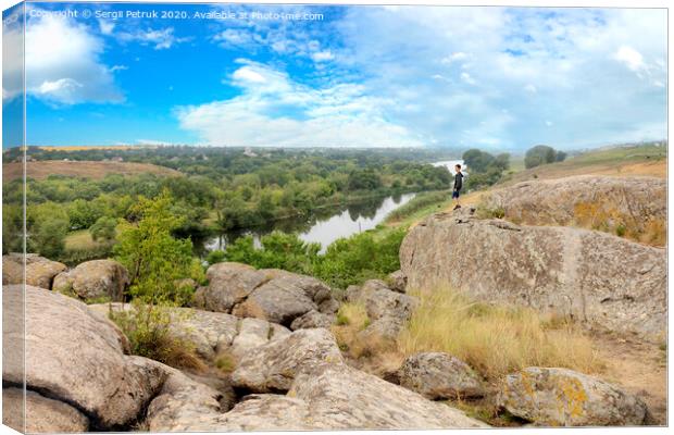 The teenager stands on top of a large stone boulder on the bank of the Southern Bug River and looks at the river below Canvas Print by Sergii Petruk