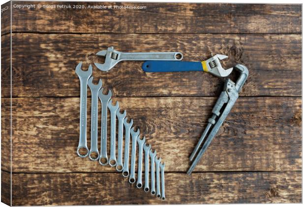 Set of combination wrenches and old adjustable wrenches on an old wooden background Canvas Print by Sergii Petruk