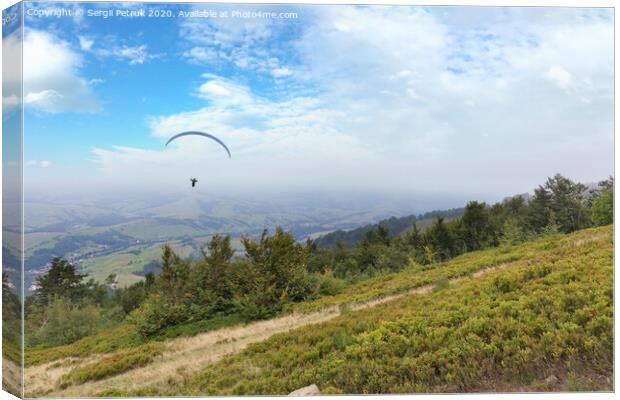 A flying paraglider against the blue sky, in the morning fog of the Carpathian Mountains Canvas Print by Sergii Petruk