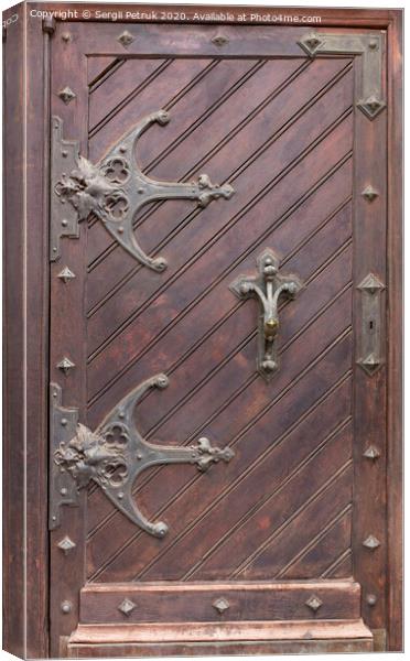 Ancient antique wooden doors with wrought iron loops and cross bars. Canvas Print by Sergii Petruk