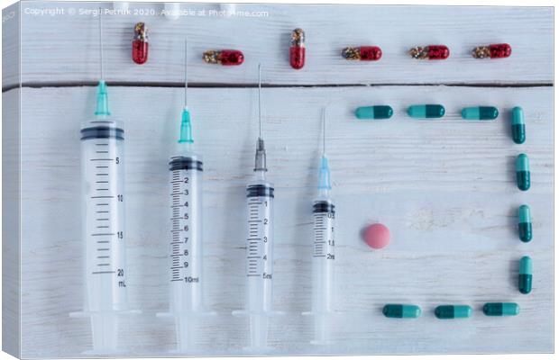 Medical syringes, capsules, pills lie vertically on a white roughly painted wooden table. Canvas Print by Sergii Petruk
