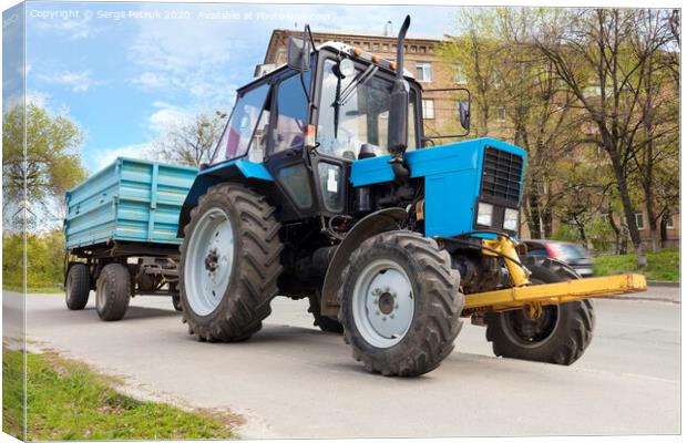An old small blue tractor with a trailer stands on the side of the road Canvas Print by Sergii Petruk