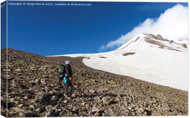 The tourist rises up the mountainside to the snow-capped summit Canvas Print by Sergii Petruk