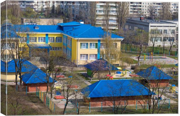 Bright blue roof of kindergarten against the background of gray urban high-rise buildings Canvas Print by Sergii Petruk