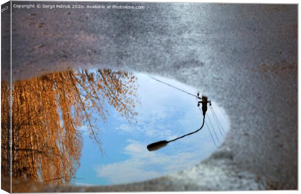 Reflection of the sky, the silhouette of a street lamp and a tree sunlit in a puddle on asphalt. Canvas Print by Sergii Petruk