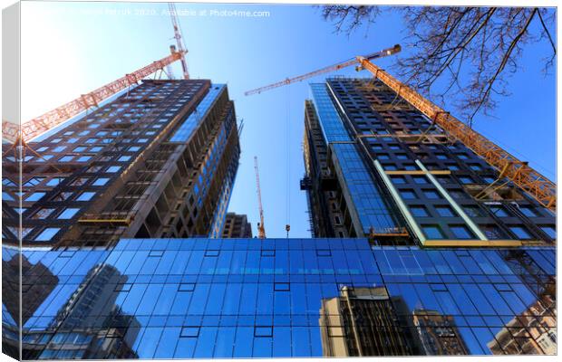 The glass facade, a reflection of the blue sky and cranes near a modern concrete building under construction. Canvas Print by Sergii Petruk