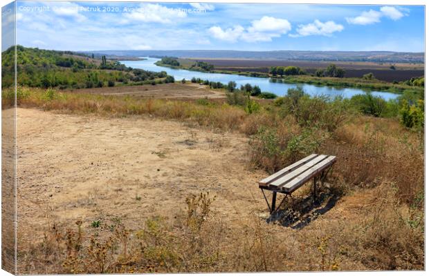 View of a wooden bench on a high river bank on a bright autumn day. Rural autumn landscape. Canvas Print by Sergii Petruk