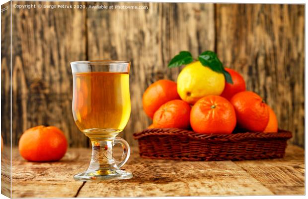 Citrus tea in a glass cup on a background of mandarin and lemon fruits in blur. Canvas Print by Sergii Petruk