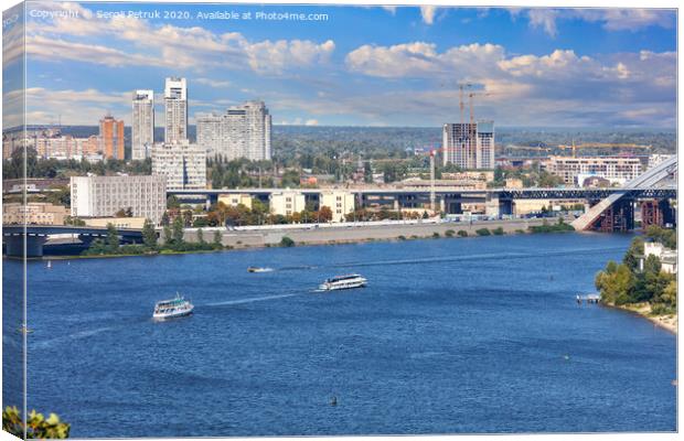 Pleasure boats run along the water surface of the Dnipro along the city embankment of Kyiv against the backdrop of a bright, beautiful sky and city buildings. Canvas Print by Sergii Petruk
