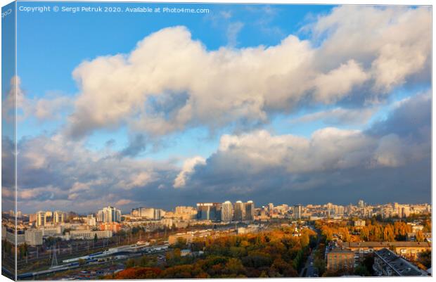The colorful cityscape of autumn Kyiv, the sun's rays from behind gray clouds catch and brightly illuminate the orange foliage of the city park. Canvas Print by Sergii Petruk