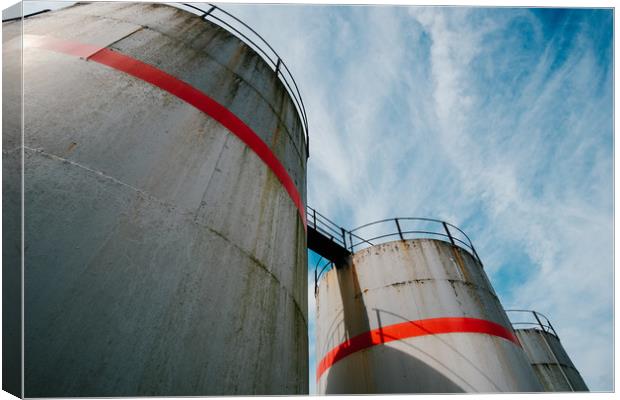 Industrial fuel tanks against a blue sky Canvas Print by Tom Radford