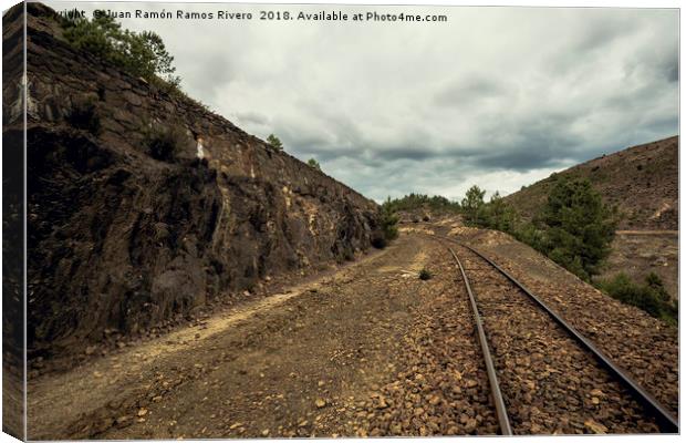 Old train tracks between mountains on a cloudy day Canvas Print by Juan Ramón Ramos Rivero