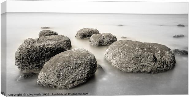 Boulders on smooth sea Canvas Print by Clive Wells