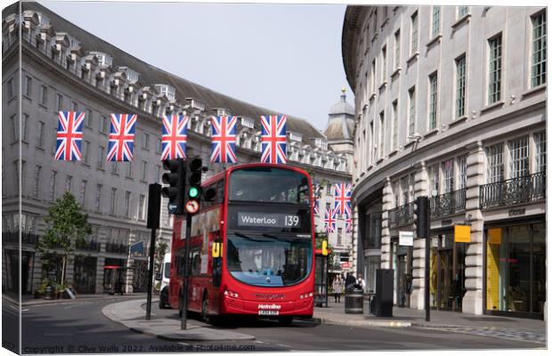 London bus under the flags Canvas Print by Clive Wells