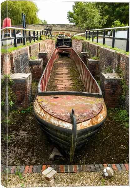 Abandoned shell of narrowboat at Stoke Brurne in N Canvas Print by Clive Wells