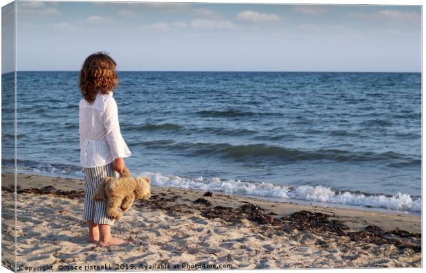 little girl with teddy bear standing on beach and  Canvas Print by goce risteski