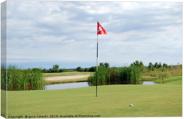 golf course with red flag and ball Canvas Print by goce risteski