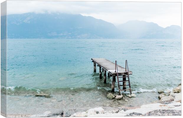 Quiet shore of Lake Garda on a rainy day near the empty jetty. Canvas Print by Joaquin Corbalan