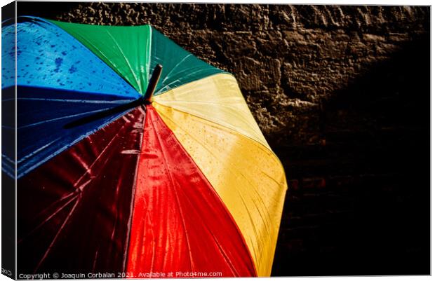 Open umbrella against the intense sun with bright colors and dar Canvas Print by Joaquin Corbalan