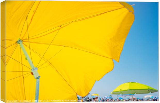 Beach holiday background, with a large yellow umbrella in the fo Canvas Print by Joaquin Corbalan