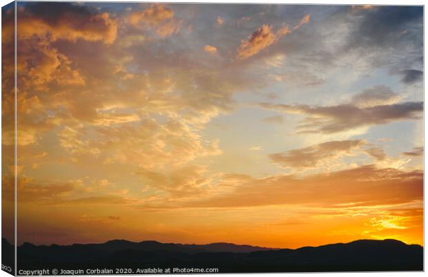 Beautiful sunset with the sun of orange tones behind the mountains and deep blue sky Canvas Print by Joaquin Corbalan