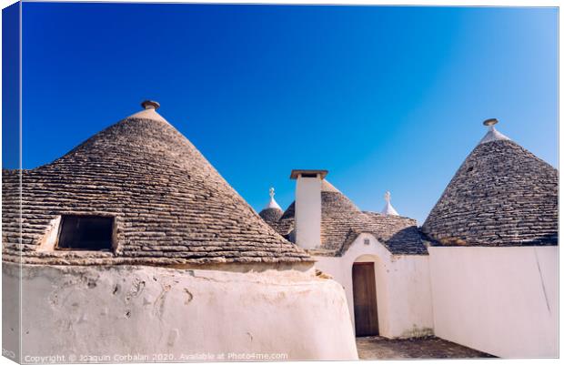 Stone tiles cover the roofs of the trulli in Alberobello, an Italian city to visit on a trip to Italy. Canvas Print by Joaquin Corbalan