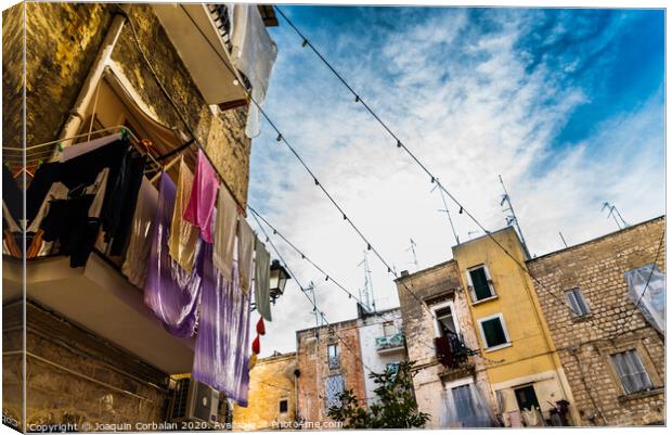 Colorful clothes tended to dry on the balconies of the old houses of an Italian city in the Mediterranean. Canvas Print by Joaquin Corbalan