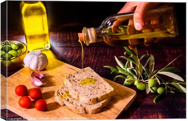 A Mediterranean cook prepares a slice of bread with virgin olive oil, tomatoes and garlic, a traditional breakfast in the Mediterranean countries. Canvas Print by Joaquin Corbalan