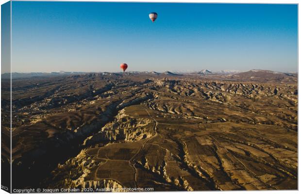 Colorful balloons flying over mountains and with blue sky in cappadocia Canvas Print by Joaquin Corbalan