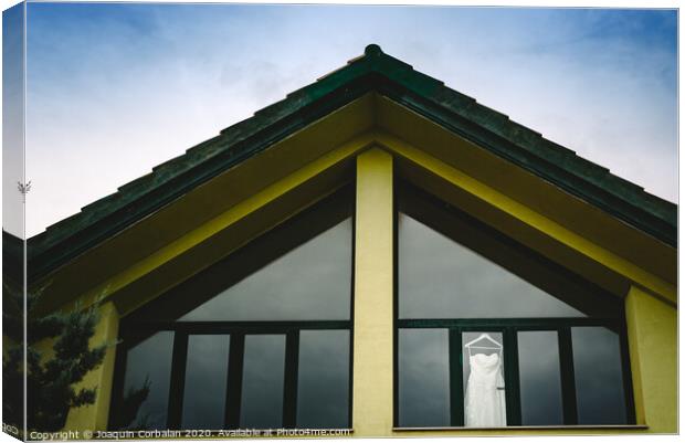 Wedding dress hanging from a window seen from outside with intense blue sky. Canvas Print by Joaquin Corbalan