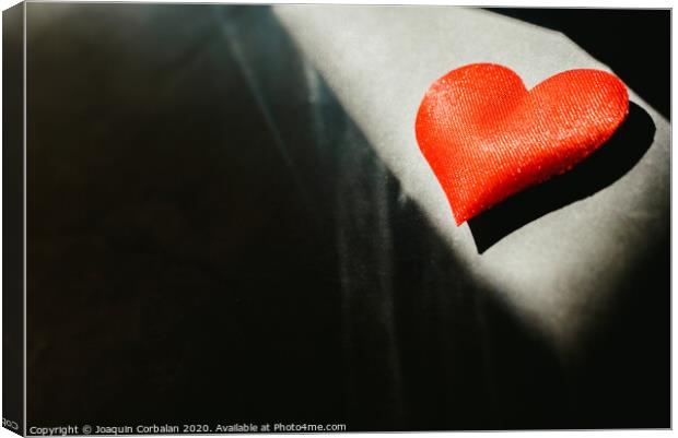 Red hearts isolated dark background illuminated by a ray of sun to use in the background, with a lot of empty space copy space. Canvas Print by Joaquin Corbalan
