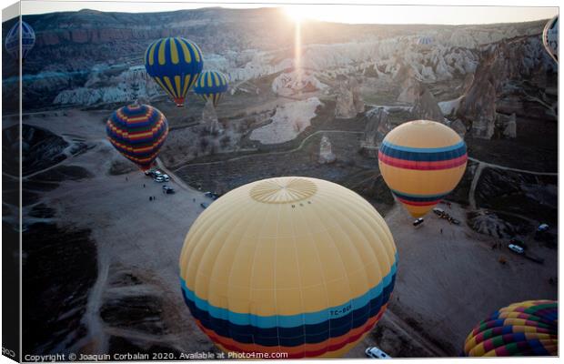 Hot air balloons for tourists flying over rock formations at sunrise in the valley of Cappadocia. Canvas Print by Joaquin Corbalan