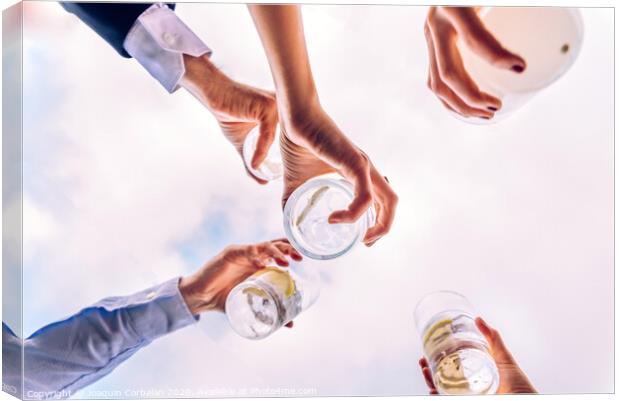 Group of friends toasting with a few glasses of alcohol with the sky in the background, seen from below. Canvas Print by Joaquin Corbalan