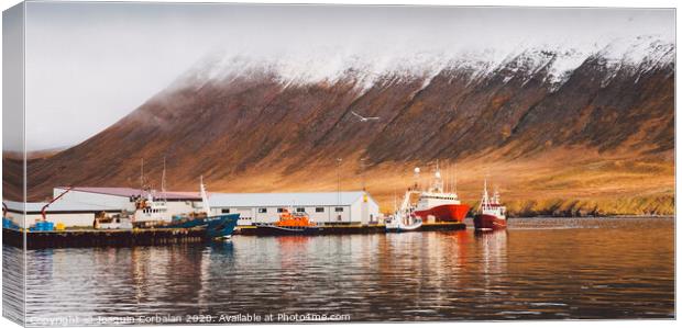 Fishing port of the village of Seydisfjordur, in Iceland, with vibrant colors and reflections in the sea of fishing boats. Canvas Print by Joaquin Corbalan