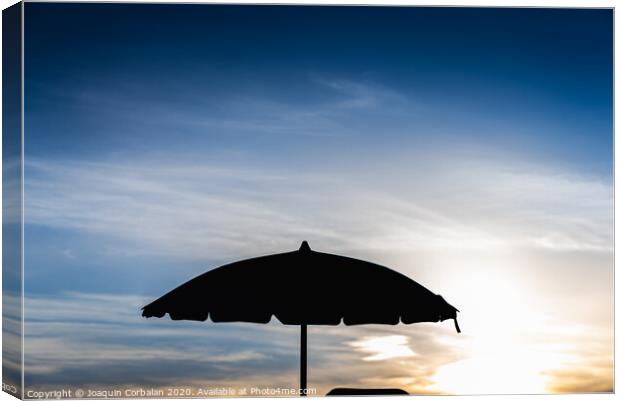 Silhouette of beach umbrella against backlight on a hot summer day. Canvas Print by Joaquin Corbalan