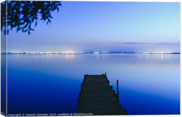 Pier on a lake at sunset with calm water and reflections of relaxing lights. Canvas Print by Joaquin Corbalan