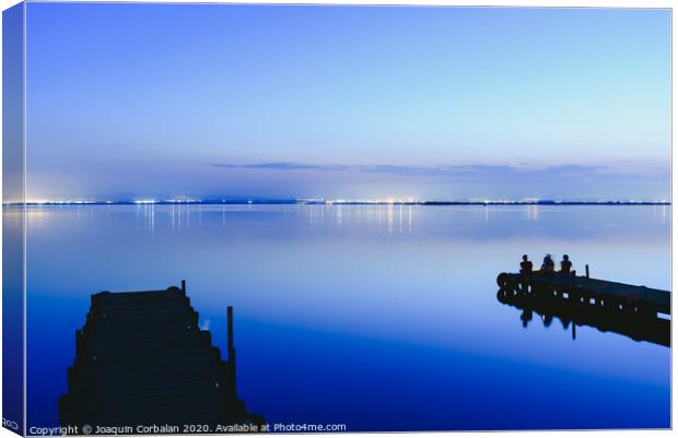 People resting relaxed on a pier on a lake at sunset with calm water Canvas Print by Joaquin Corbalan